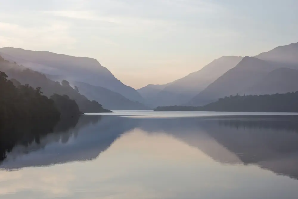 Lac liniștit, învăluit în ceață, în lumina dimineții
